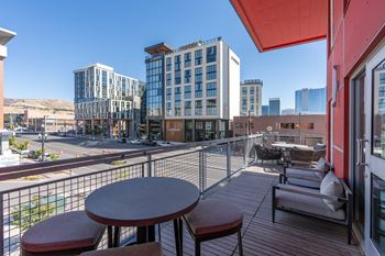 A balcony with a table and chairs overlooks a city street.